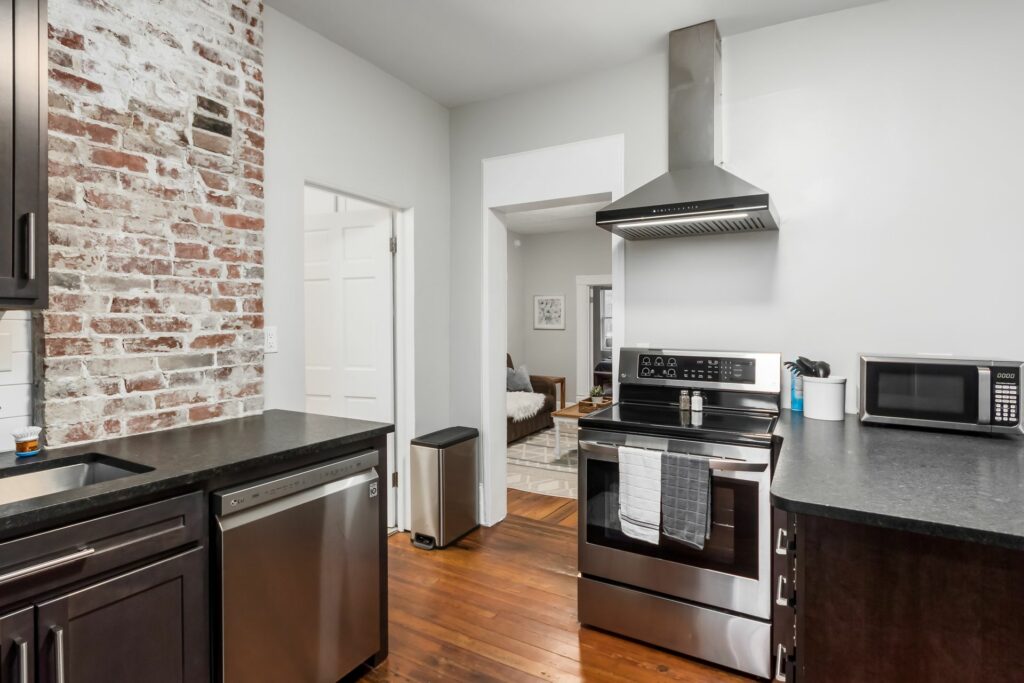 A kitchen with stainless steel appliances and brick wall.