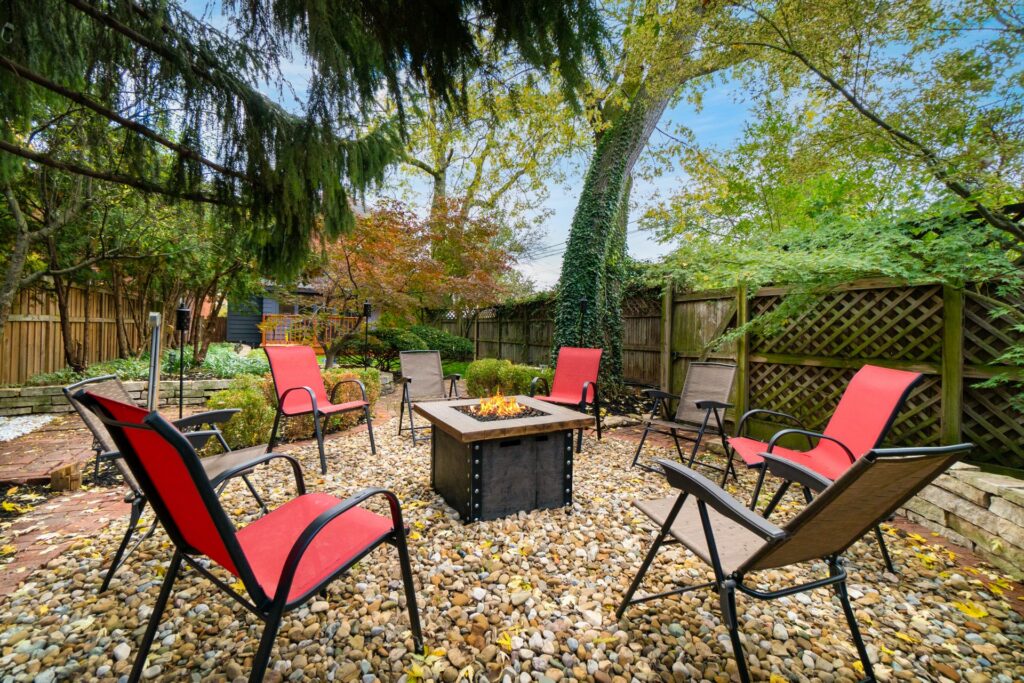 A group of chairs and tables around an outdoor fire pit.