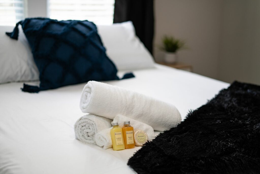 A bed with white towels and two bottles of lotion.
